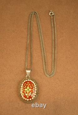 Beautiful old pendant in solid silver and Bressan enamels on a red background
